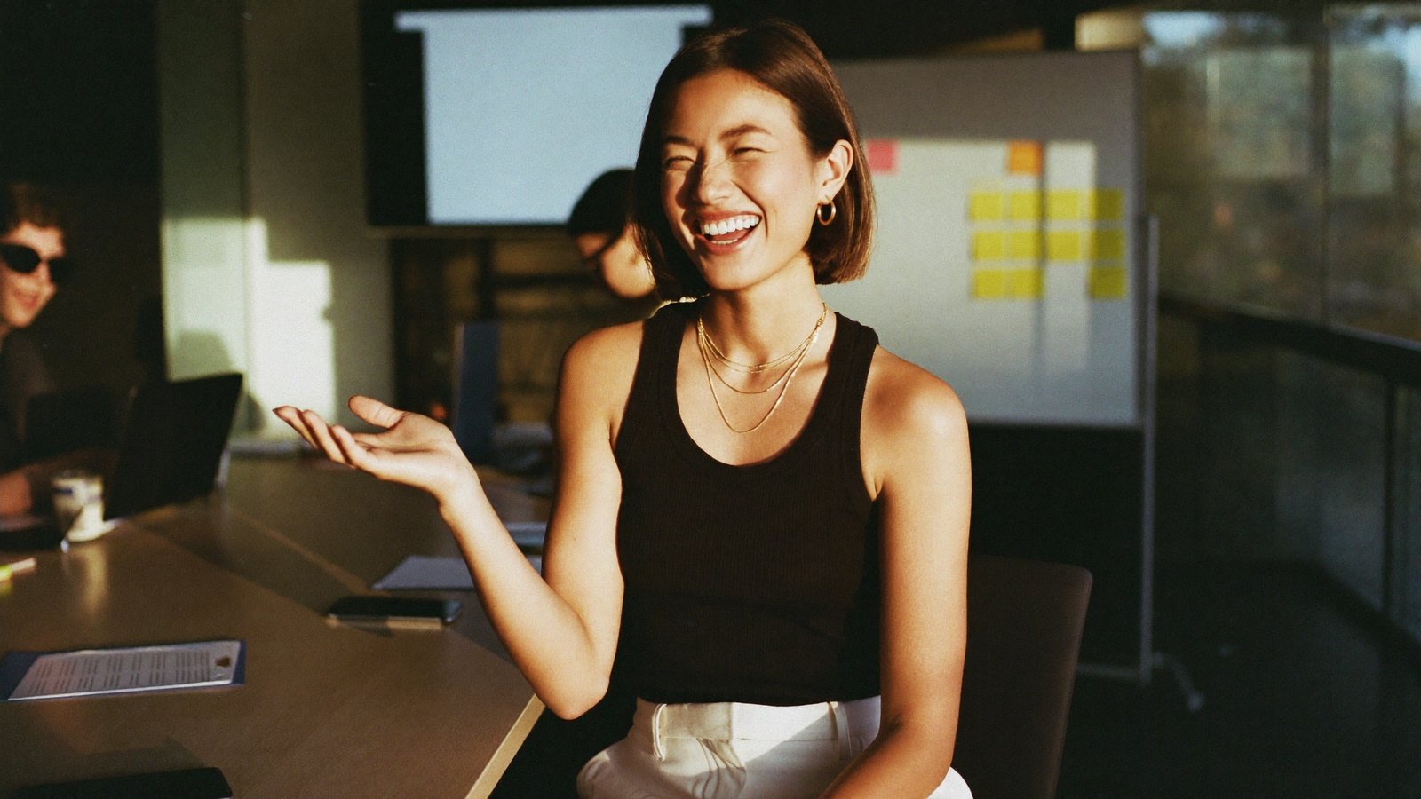 A founder recording a vertical video on a phone in a glass meeting room at golden hour