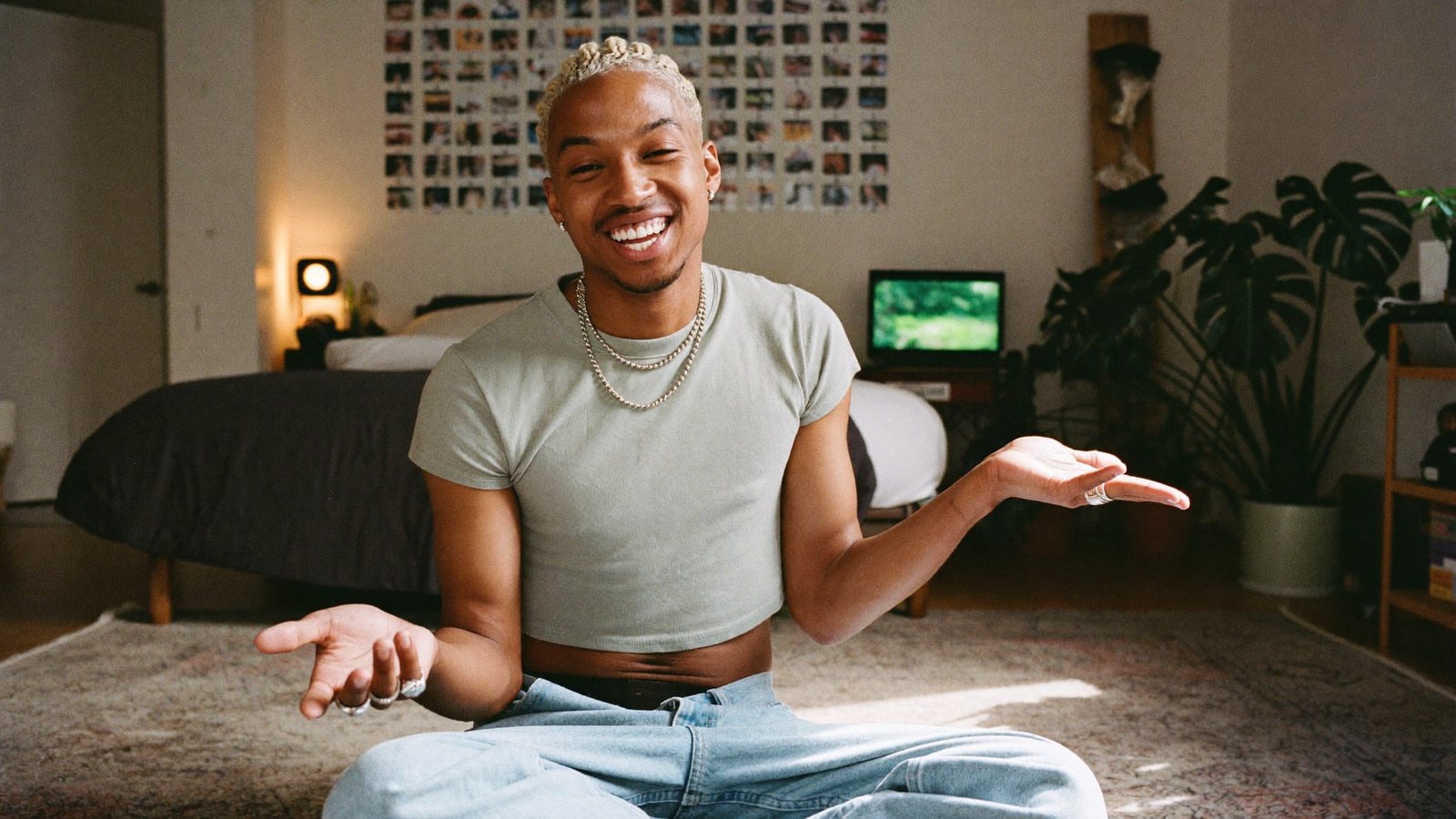 A full-time creator in a bedroom studio with a ring light and LED strips laughing and gesturing at a phone on a tripod